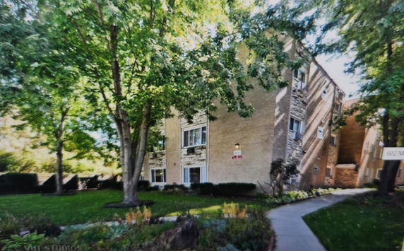 Front view of a multi-story residential building with brick exterior and large windows.