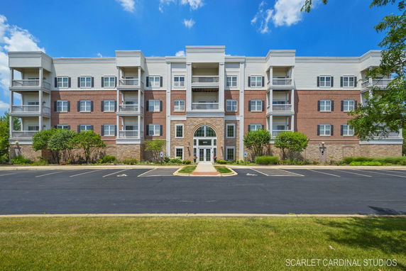 Front view of a multi-story brick building with balconies and large central entrance.