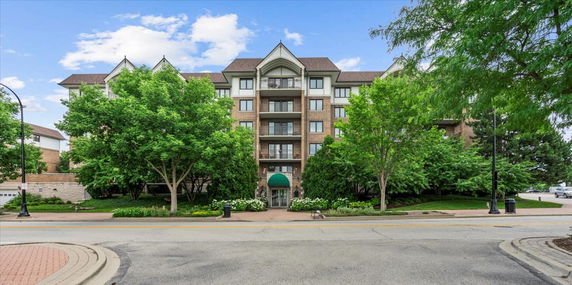 Front view of a multi-story residential building with trees and landscaping.