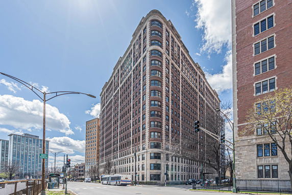 Front view of a large multi-story brick building on a city street corner.