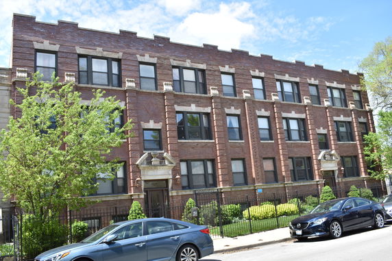 Front view of a multi-story brick building with large windows.