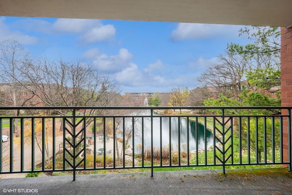 View from a balcony overlooking a pond and surrounding landscape.