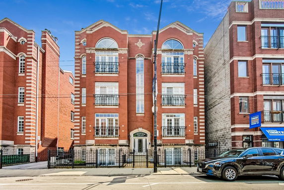 Front view of a multi-story brick building with large windows and decorative balconies.