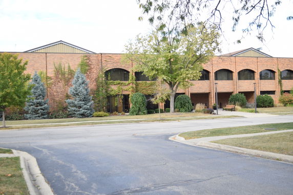 Front view of a two-story brick building with large windows and greenery.