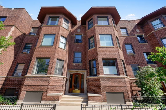 Front view of a multi-story brick building with large windows.