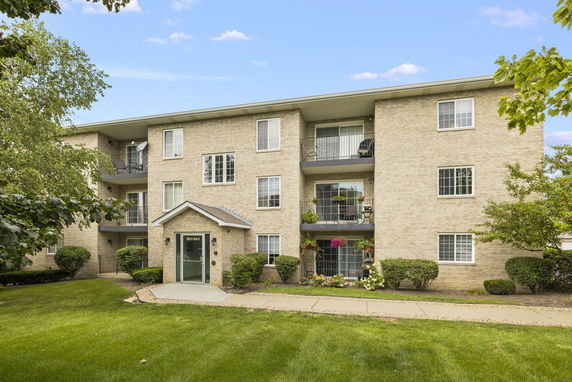 Front view of a three-story brick apartment building with balconies.