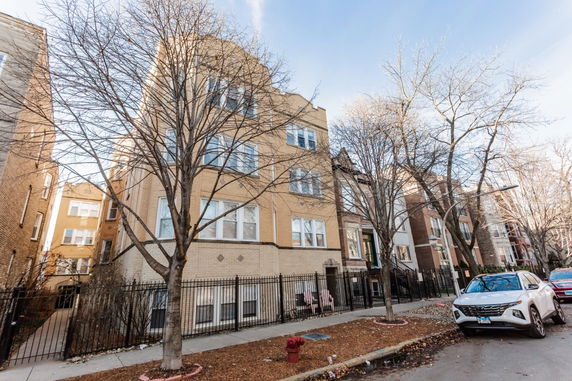 Front view of a multi-story residential building with a brick facade and multiple windows.