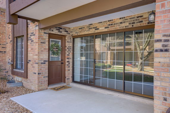 Front view of a house with a brown door and sliding glass doors.