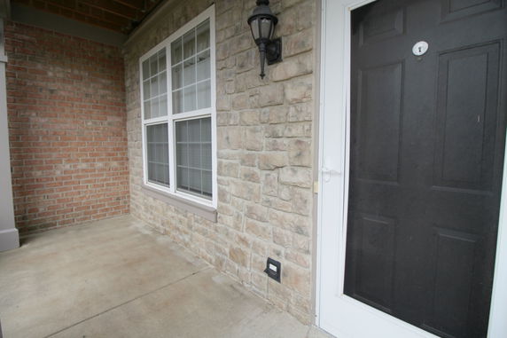 Front view of a brick and stone exterior with a black door and windows.