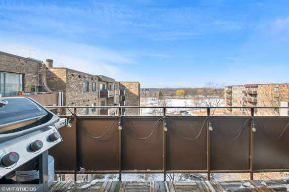 View from a balcony overlooking residential buildings and a snowy landscape.