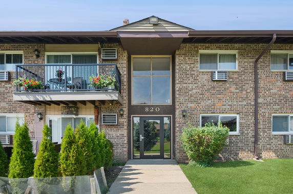 Front view of a two-story brick apartment building with a balcony.