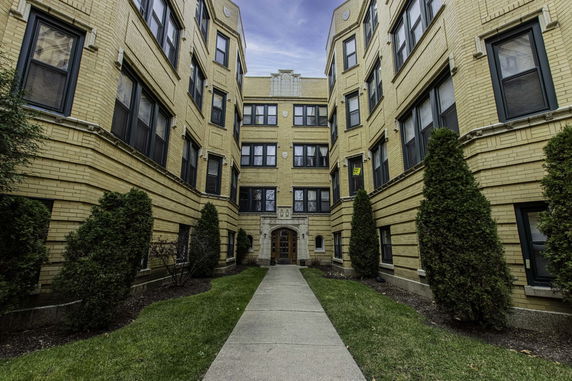 Front view of a multi-story apartment building with a central entrance.