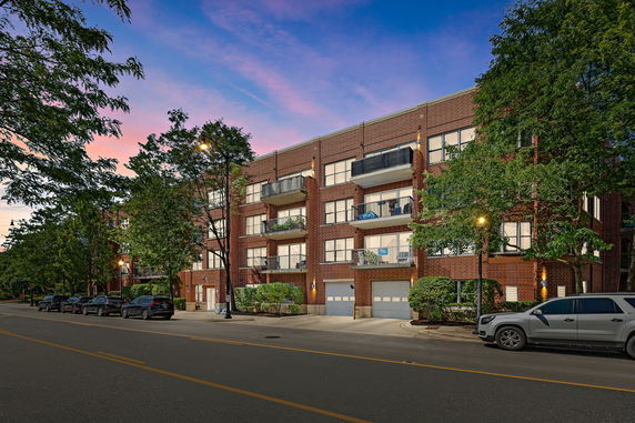 Front view of a multi-story brick apartment building with balconies.