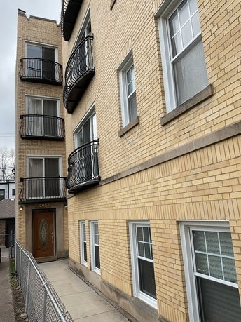 Front view of a three-story brick building with balconies.