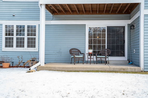 Front view of a house with blue siding and a small patio area.