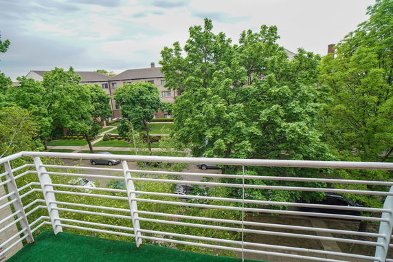View from a balcony showing trees and residential buildings.