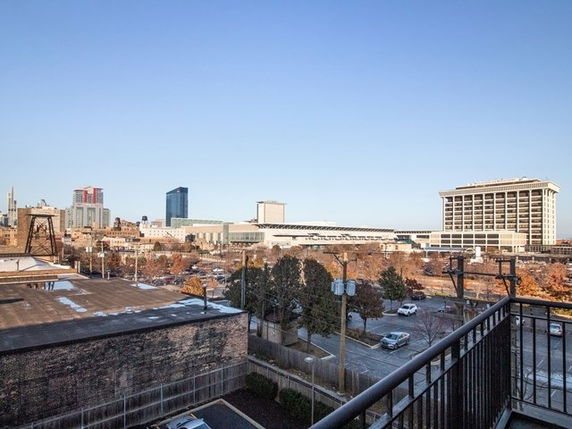Panoramic view from a building overlooking a cityscape with distant buildings and a clear sky.
