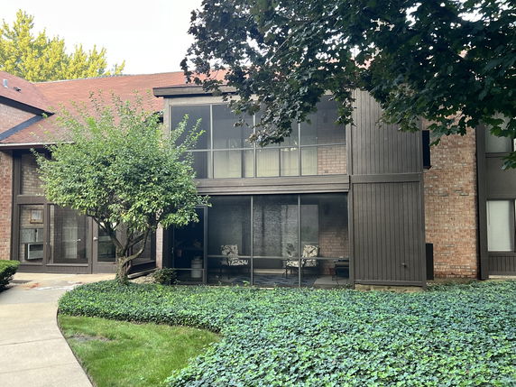 Front view of a two-story building with a brown exterior and large windows.