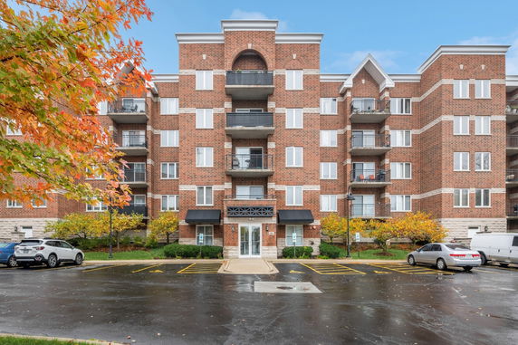 Front view of a multi-story brick apartment building with balconies.