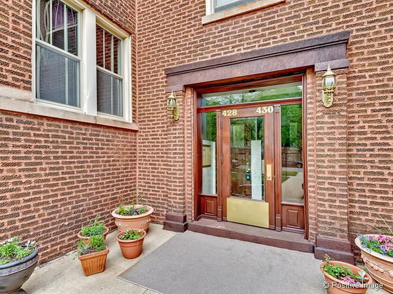 Front view of a brick building entrance with double wooden doors.