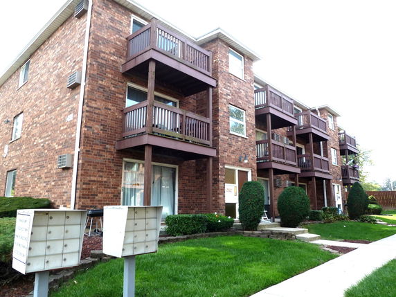Front view of a multi-story brick apartment building with balconies.