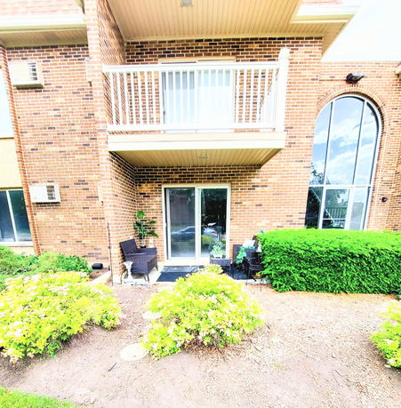 Front view of a brick two-story building with balcony and large windows.