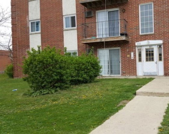 Front view of a multi-story brick building with balconies and entrance.
