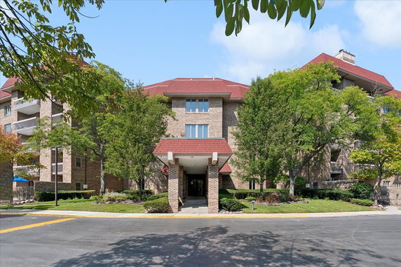 Front view of a multi-story brick building with a red roof and entrance canopy.
