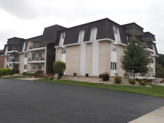 Front view of a multi-story apartment building with white brick facade and dark roofing.