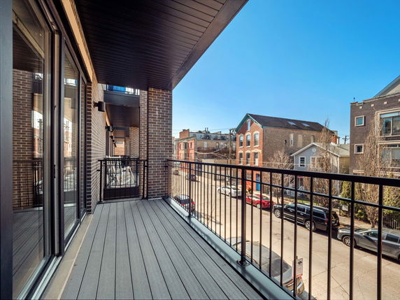 View from a balcony overlooking a street with residential buildings.