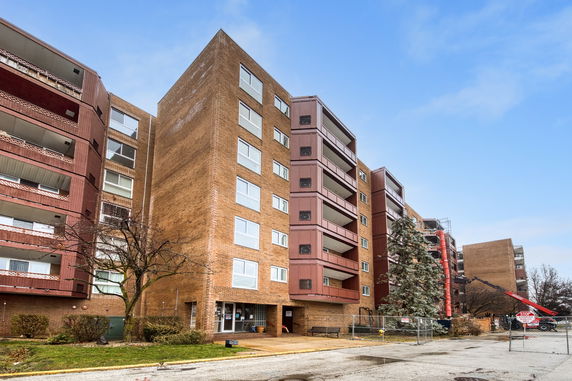 Front view of a multi-story apartment building with brown and red brick exterior.