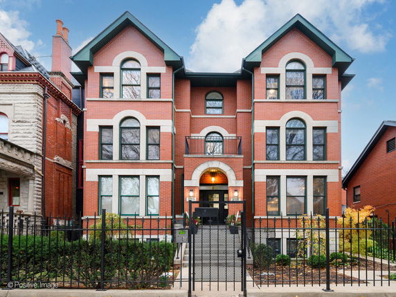 Front view of a three-story brick building with arched windows and a central entrance.