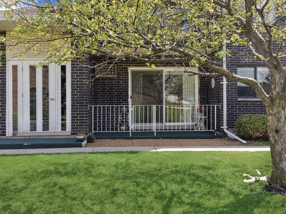 Front view of a house with dark brick exterior and white railing.