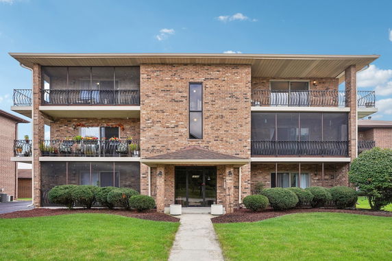 Front view of a multi-story brick apartment building with balconies.