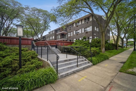 Front view of a multi-story residential building with stairs and railing.