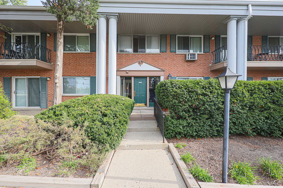 Front view of a building with brick facade, green door, and white columns.
