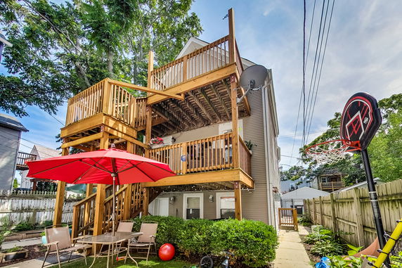Back view of a multi-story house with wooden balconies and patio furniture.