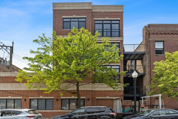 Front view of a multi-story brick building with large windows and metal balconies.