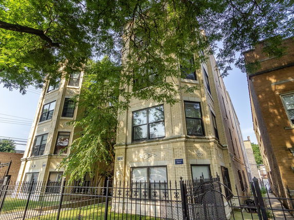 Front view of a multi-story building with large windows and a gated entrance.
