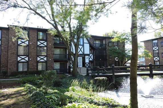 Front view of a multi-story apartment building with brick and wood detailing.