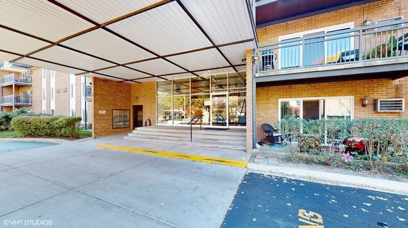 Front view of a building with a covered entrance and large glass windows.