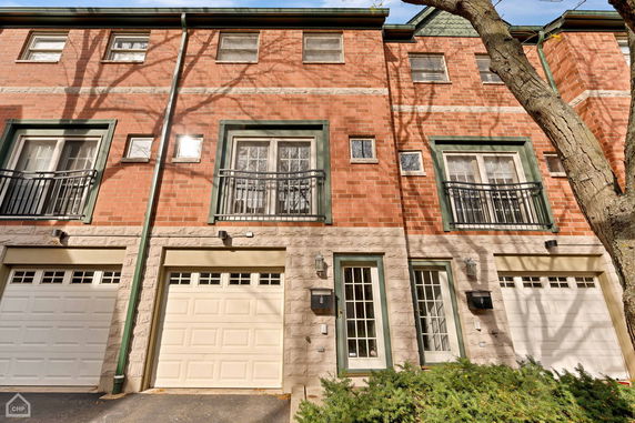 Front view of a multi-story brick house with two garages and balconies.
