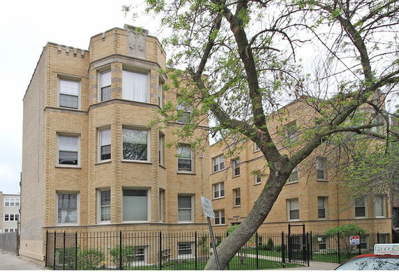 Front view of a multi-story brick apartment building with bay windows.