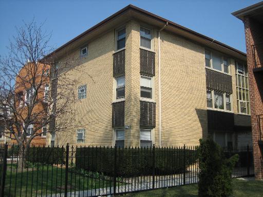 Front view of a multi-story building with brick exterior and a fence.