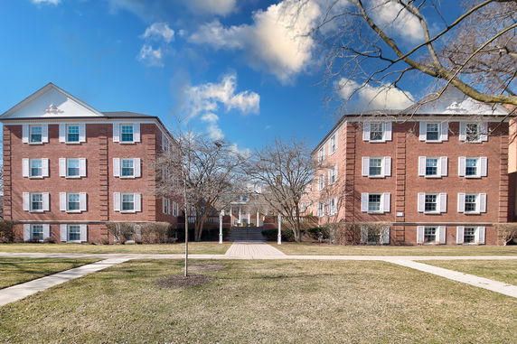 Front view of two adjacent brick apartment buildings with multiple stories and symmetrical windows.