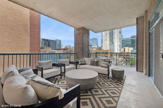 View from a building balcony with seating area overlooking cityscape.