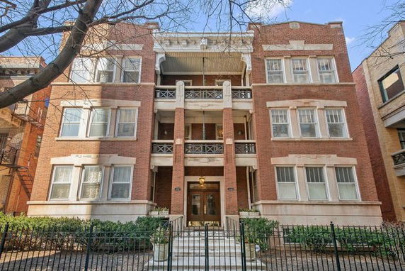 Front view of a multi-story brick building with balconies and decorative railings.