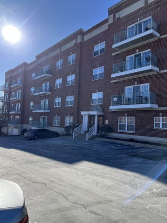 Front view of a multi-story brick apartment building with balconies.