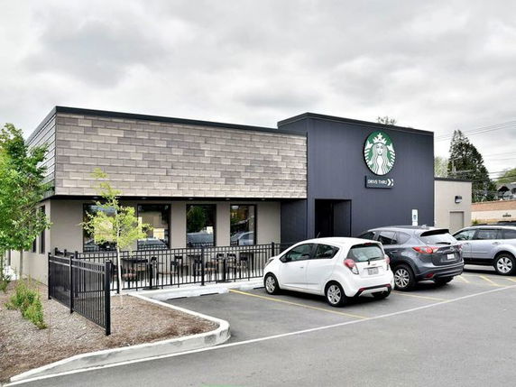 Front view of a modern commercial building with a drive-thru and parking area.