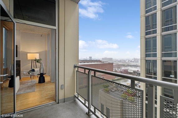 Balcony view from a high-rise apartment showing cityscape and adjacent building.